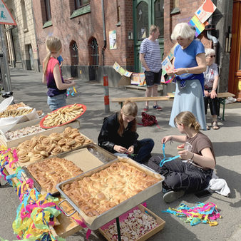 Große Bleche an Gebäck an einem Aktionsstand vor einem roten Backsteingebäude