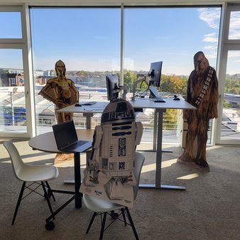ZU sehen ist ein PC-Arbeitsplatz im Open Space Bereich mit Pappfiguren von Star Wars