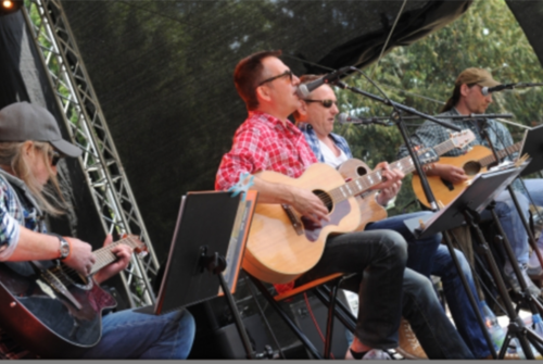 Vier Männer sitzen auf der Bühne und alle spielen Gitarre