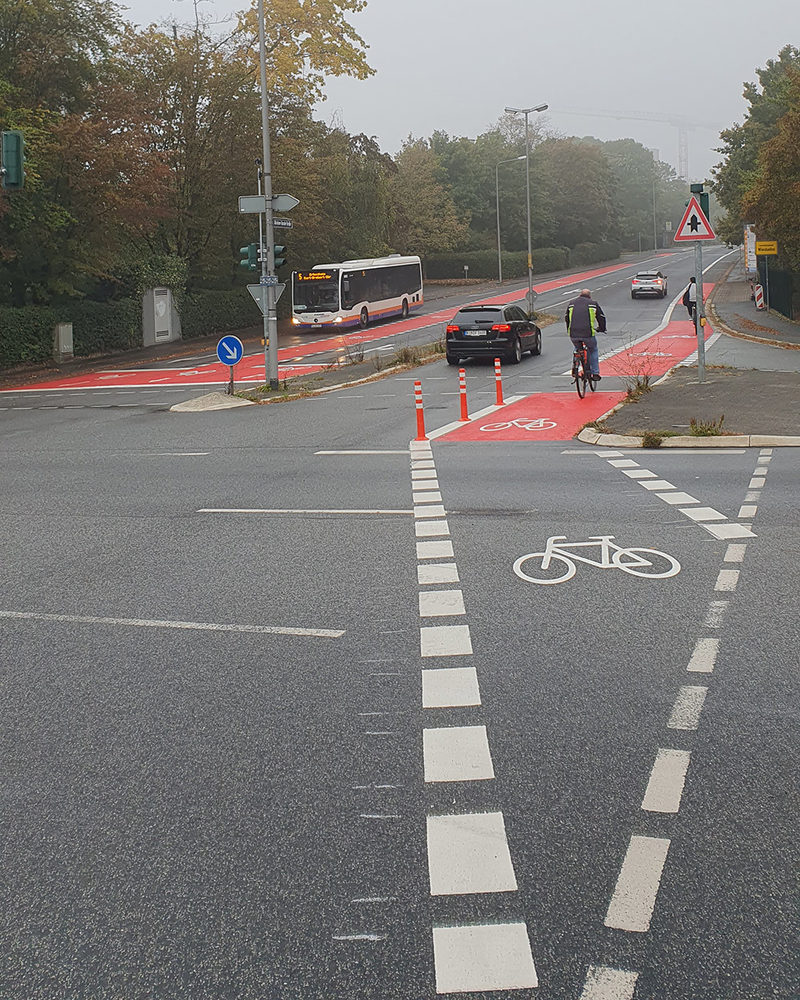 Straße mit Bus und Autos und Radfahrer.