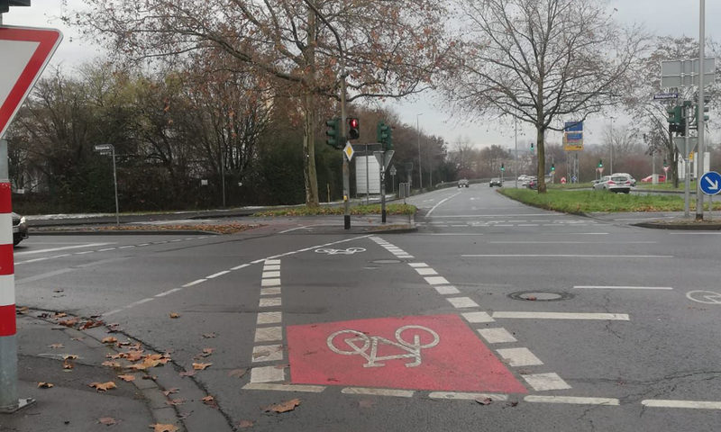 Radweg - rot einzeichnet - an einer Kreuzung mit Ampeln.