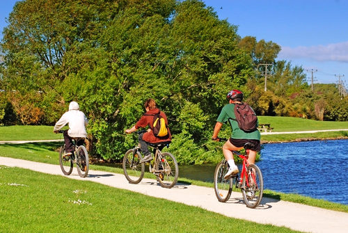 Fahrräder mieten - hier drei Radfahrer im Park am Wasser unterwegs.